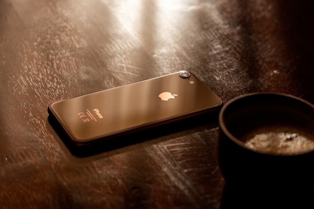 A phone and a coffee cup on a wooden table
